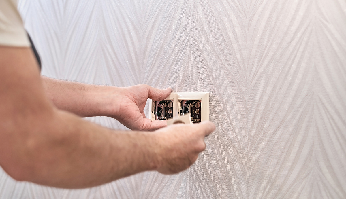 Electrical repair and install socket, outlet plug and switch. An electrician caucasian man install an outlet with pliers during a repair. Hands of the master close-up during work